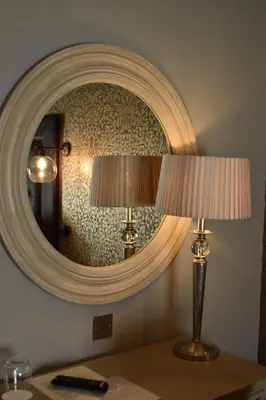 a mirror on a wall with two lamps on a table at Elveden Inn in Elveden