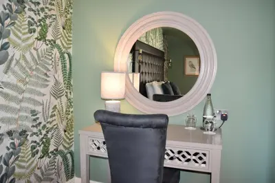 a mirror on a wall next to a desk with a chair at Elveden Inn in Elveden