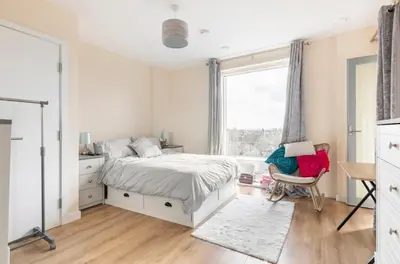 a white bedroom with a bed and a window at Comfy city room in Cambridge