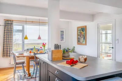 a kitchen with a view of the ocean and a dining room at Chicoutimi in Thorpeness