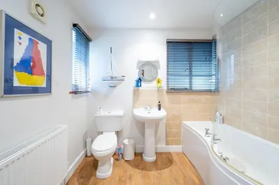 a bathroom with a toilet and a tub and a sink at Chicoutimi in Thorpeness