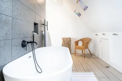 a bathroom with a white tub and a chair at Chicoutimi in Thorpeness