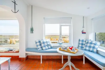 a living room with blue and white pillows and a table at Chicoutimi in Thorpeness