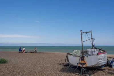 a boat sitting on the beach with two people at Chicoutimi in Thorpeness