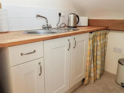 a kitchen with white cabinets and a sink at Woodland Retreat Lodge in Woodbridge