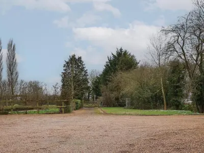 a dirt road with trees in the background at Woodland Retreat Lodge in Woodbridge