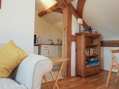 a living room with a table and a kitchen at Woodland Retreat Lodge in Woodbridge