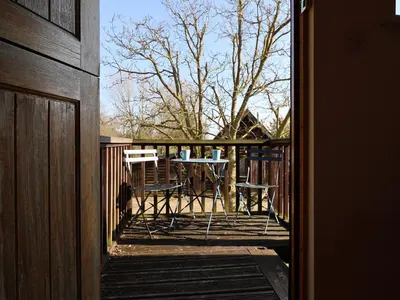 a porch with a table and chairs on a deck at Woodland Retreat Lodge in Woodbridge