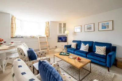 a living room with a blue couch and a table at The Nest, Aldeburgh - Prime location close to the beach and town amenities - Aldeburgh Coastal Cottages in Aldeburgh