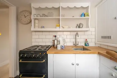 a kitchen with a black stove and a sink at The Nest, Aldeburgh - Prime location close to the beach and town amenities - Aldeburgh Coastal Cottages in Aldeburgh