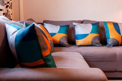 a couch with colorful pillows on it at Pass the Keys Spacious and modern house with Free Parking in Cambridge