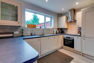 a kitchen with white cabinets and a large window at Pass the Keys Spacious and modern house with Free Parking in Cambridge