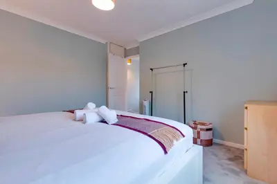 a bedroom with a white bed with a teddy bear on it at Pass the Keys Spacious and modern house with Free Parking in Cambridge