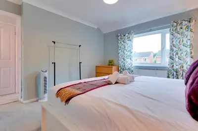 a large white bed in a room with a window at Pass the Keys Spacious and modern house with Free Parking in Cambridge