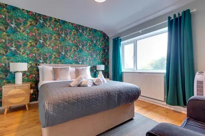 a bedroom with a bed and a large window at Pass the Keys Spacious and modern house with Free Parking in Cambridge
