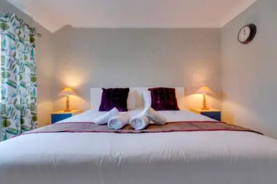 a bedroom with a large white bed with two lamps at Pass the Keys Spacious and modern house with Free Parking in Cambridge