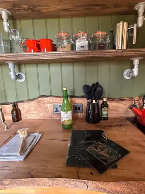 a wooden counter top with a bottle of wine on it at 'Russet' Hut on fruit farm in Charsfield