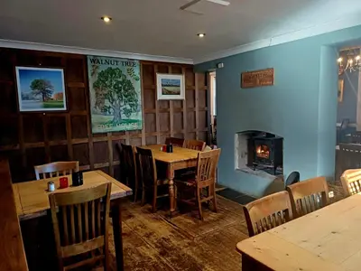 a restaurant with wooden tables and a fireplace at the walnut tree in Worlington