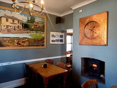 a dining room with a table and a clock on the wall at the walnut tree in Worlington