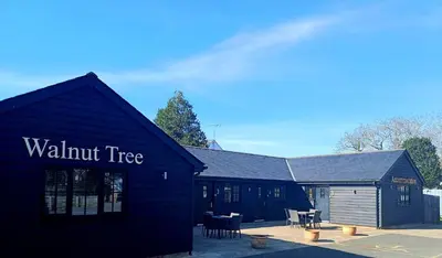 a black building with a walnut tree sign on it at the walnut tree in Worlington