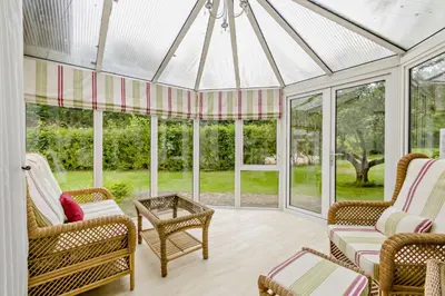 a conservatory with a glass roof with chairs and a table at Finest Retreats - The House at No 47 in West Wickham