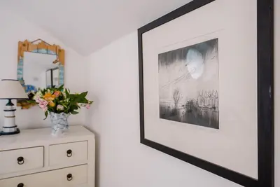 a picture frame hanging on a wall next to a dresser at Art Cottage, Aldeburgh in Aldeburgh