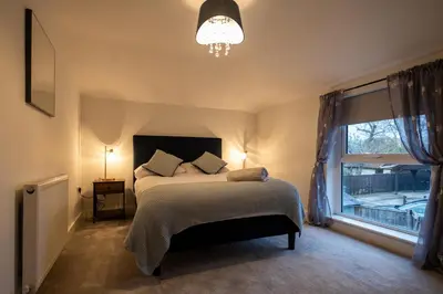 a bedroom with a bed with a chandelier and a window at High Street 200A in Wickham Market