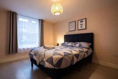 a bedroom with a bed with a large window at High Street 200A in Wickham Market