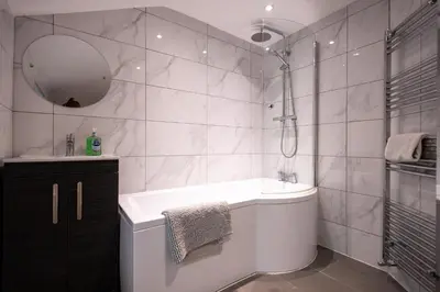 a bathroom with a tub and a sink and a mirror at High Street 200A in Wickham Market