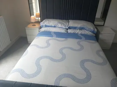 a bed with blue and white sheets and pillows at Richfield Lux in Loughton