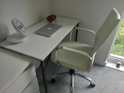 a desk with a chair and a laptop and a fan at Richfield Lux in Loughton