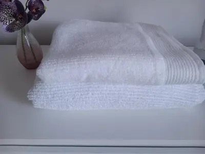 a stack of white towels on a table with a vase at Richfield Lux in Loughton