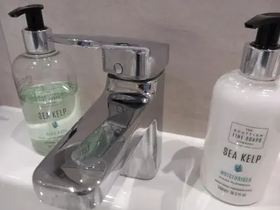 a bathroom sink with a soap dispenser and a bottle at Richfield Lux in Loughton