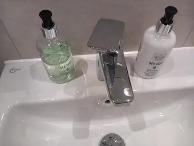 a bathroom sink with two bottles of soap and a faucet at Richfield Lux in Loughton