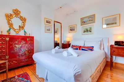 a bedroom with a large white bed and a red dresser at Pass the Keys Charming Cottage in the City Centre Free Parking in Cambridge