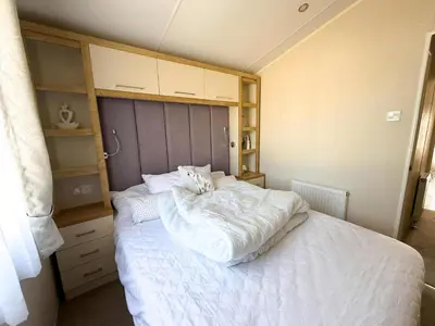 a bedroom with a large bed with white sheets at Lovely 6 Berth Caravan With Decking At Suffolk Sands Holiday Park Ref 45005Hc in Felixstowe