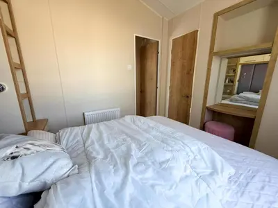 a bedroom with a white bed and a mirror at Lovely 6 Berth Caravan With Decking At Suffolk Sands Holiday Park Ref 45005Hc in Felixstowe