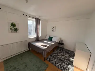 a small bedroom with a bed and a window at Essex Apartment in Loughton