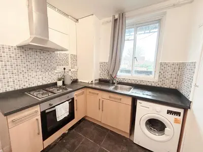 a kitchen with a sink and a washing machine at Essex Apartment in Loughton