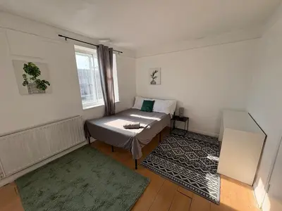 a small bedroom with a bed and a window at Essex Apartment in Loughton
