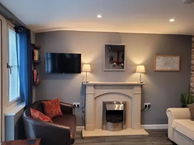 a living room with a fireplace and a tv on the wall at The Nook in Great Cornard