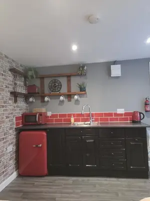 a kitchen with a sink and a red refrigerator at The Nook in Great Cornard