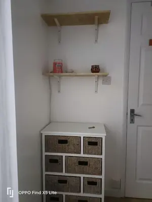 a closet with baskets and a shelf on the wall at Dolphin cottage in Nevendon