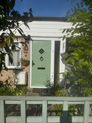 a green door on a house with a fence at Dolphin cottage in Nevendon