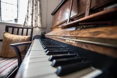 an old piano sitting next to a chair at Varley House, Saxmundham in Saxmundham