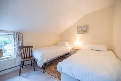 two beds in a room with a chair and a window at Varley House, Saxmundham in Saxmundham