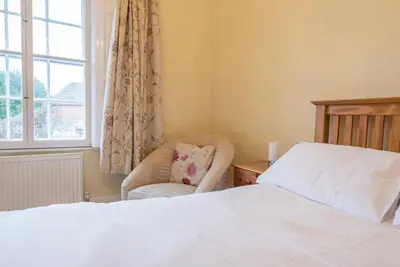 a bedroom with a bed and a chair and a window at Varley House, Saxmundham in Saxmundham