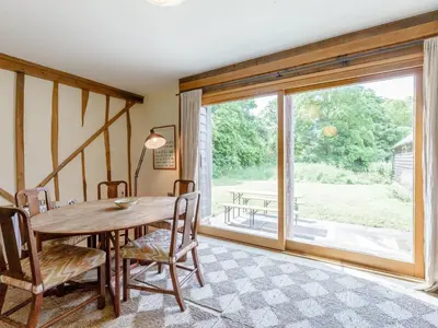 a dining room with a table and a large window at Colemans Farm Barn- Unique, Rustic & Peaceful Barn - Essex countryside in Finchingfield