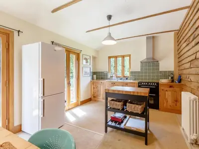 a kitchen with a white refrigerator and wooden cabinets at Colemans Farm Barn- Unique, Rustic & Peaceful Barn - Essex countryside in Finchingfield