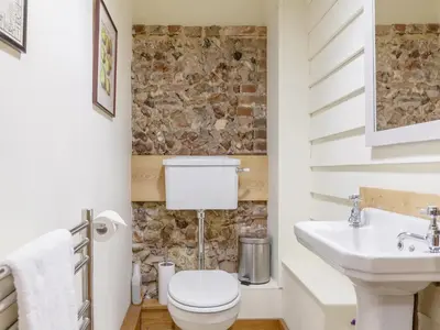 a bathroom with a toilet and a sink at Colemans Farm Barn- Unique, Rustic & Peaceful Barn - Essex countryside in Finchingfield